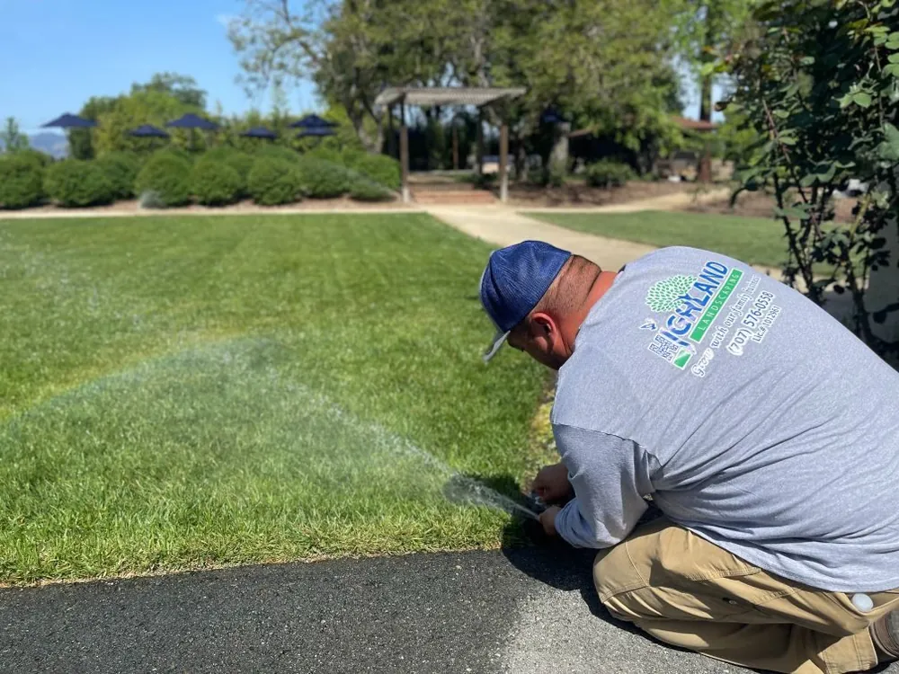A Highland crew member adjusting a sprinkler head on a freshly cut lawn