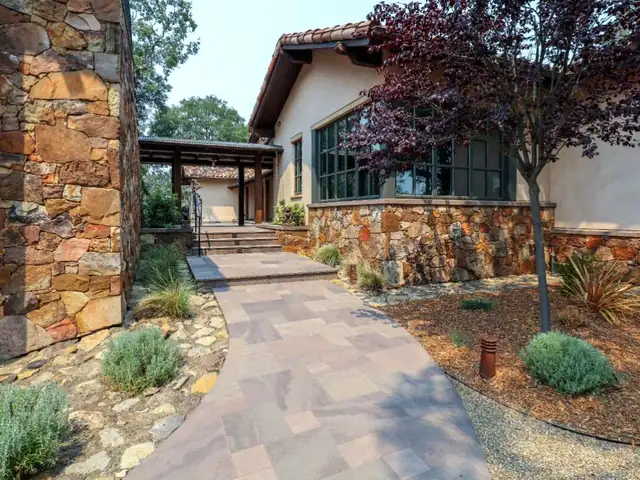 A paver walkway leading to a stone-clad entry with drought-tolerant planting